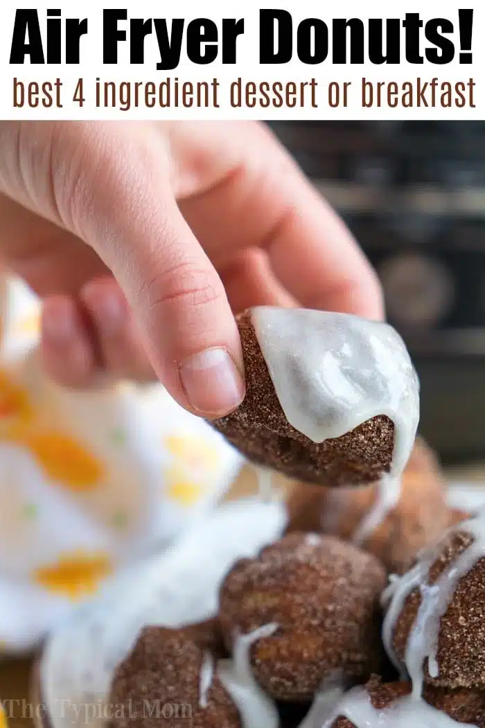A hand holds a glazed air fryer donut with more sugared donuts stacked below, perfect for those searching for easy air fryer dessert recipes.