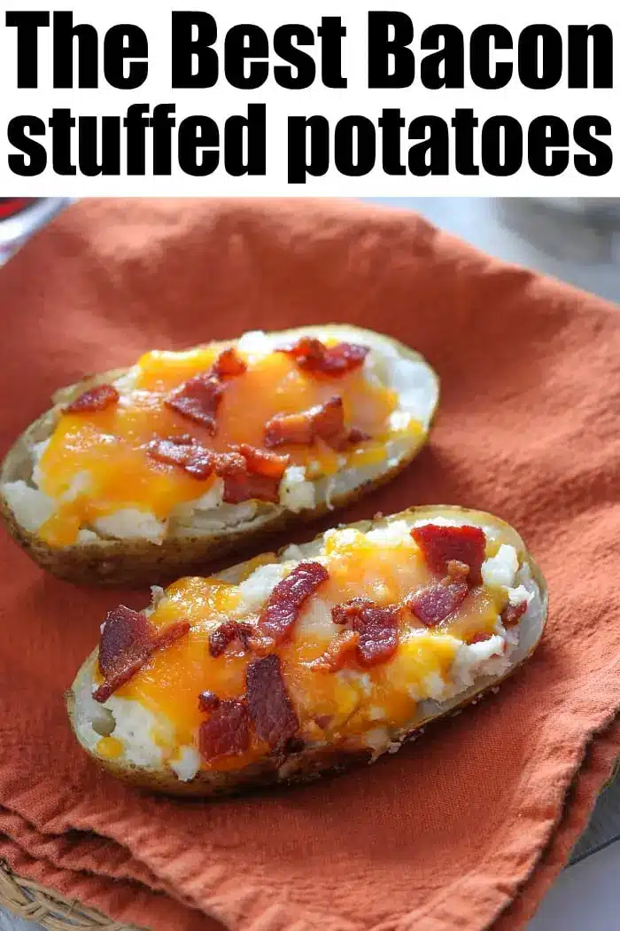 Two baked potato halves filled with mashed potato, melted cheese, and bacon pieces rest on an orange cloth. Text above reads: "Make Ahead Twice Baked Potatoes - The Best Bacon Stuffed Potatoes.