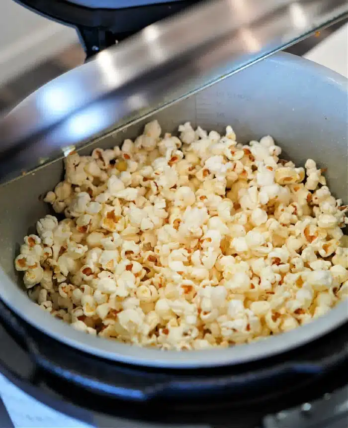 A pot filled with freshly popped popcorn inside an open Ninja Foodi pressure cooker.