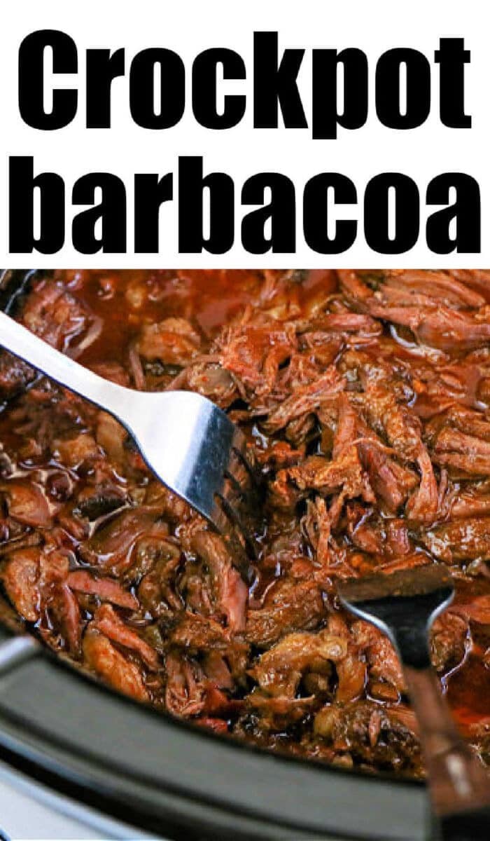 Slow cooker beef barbacoa being pulled apart with two forks, revealing tender, flavorful shredded meat.