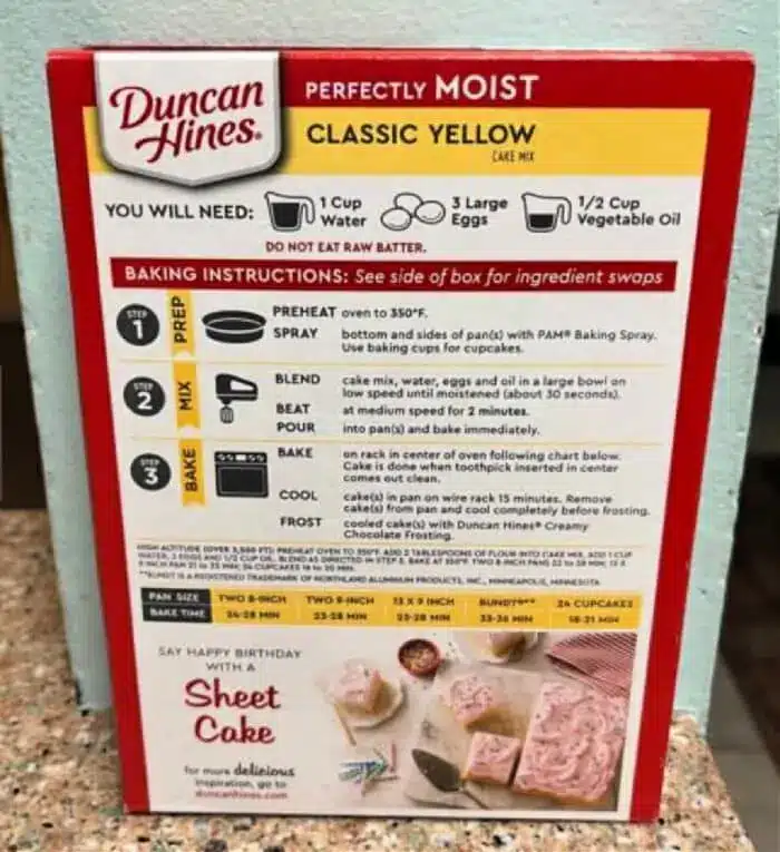 Box of Duncan Hines Perfectly Moist Classic Yellow cake mix, featuring preparation instructions and ingredients: 1 cup water, 3 large eggs, and 1/2 cup vegetable oil. Box includes baking instructions for various pan sizes and yields, plus clever box cake mix hacks to elevate your dessert game.