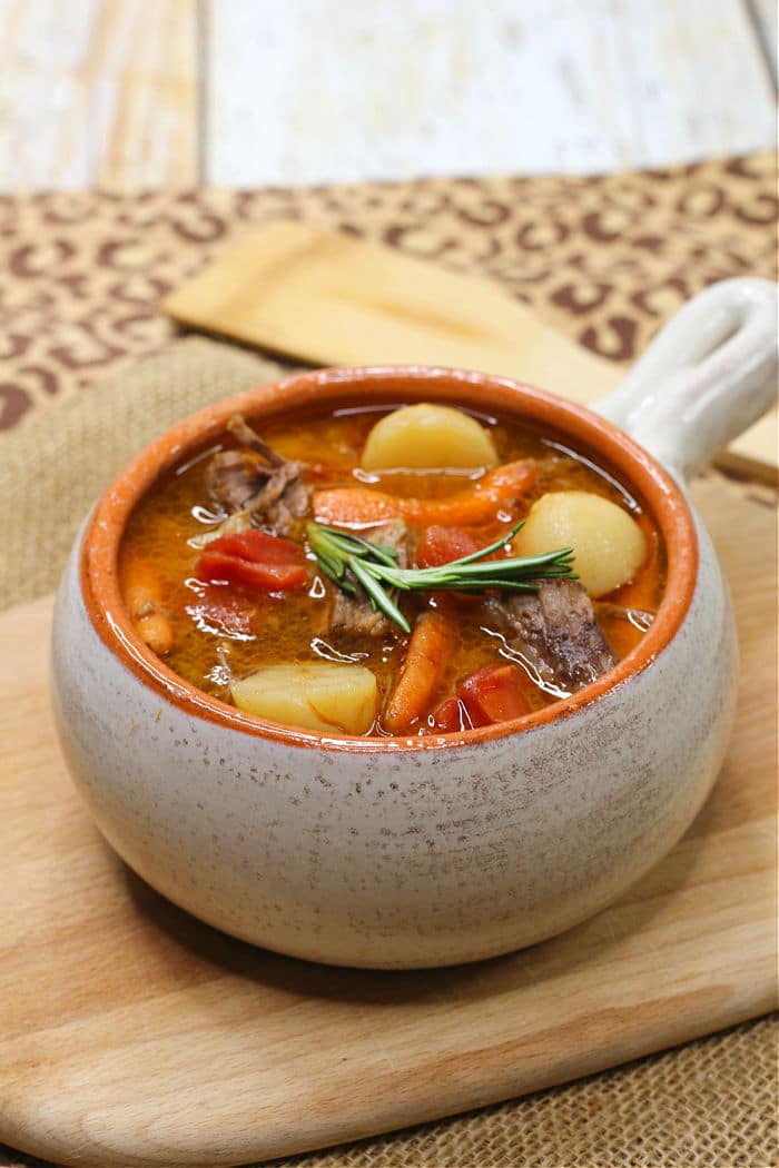 A bowl of beef stew with potatoes, carrots, and a sprig of rosemary, perfect for instant pot dinner recipes.