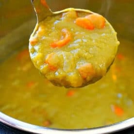 A ladle scoops thick Instant Pot Split Pea Soup Recipe with carrots from an Instant Pot.