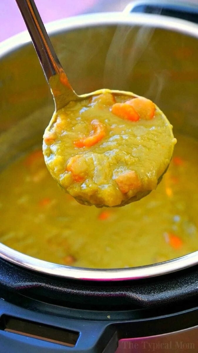 Instant Pot split pea soup recipe with ham is so easy to make and my kids love it! Throw it in your pressure cooker for 17 minutes and it's the perfect healthy soup made with dried peas that require no soaking beforehand. Fresh homemade split pea soup in less than 20 minutes! #instantpotrecipes #instantpot #pressurecooker #splitpeasoup #soup #homemade #thetypicalmom A ladle scoops thick Instant Pot Split Pea Soup Recipe with carrots from an Instant Pot.