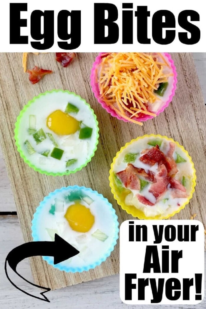 BEST egg bites cooked in your air fryer and filled with bacon, cheese and onions are the best low carb and keto breakfast idea ever! Like Starbucks egg bites but customized! #airfryer #airfryerrecipes #ninjafoodirecipes #eggbites #starbuckseggbites #airfryereggbites Four silicone muffin cups filled with eggs, veggies, cheese, and bacon on a wooden board, labeled air fryer egg bites.