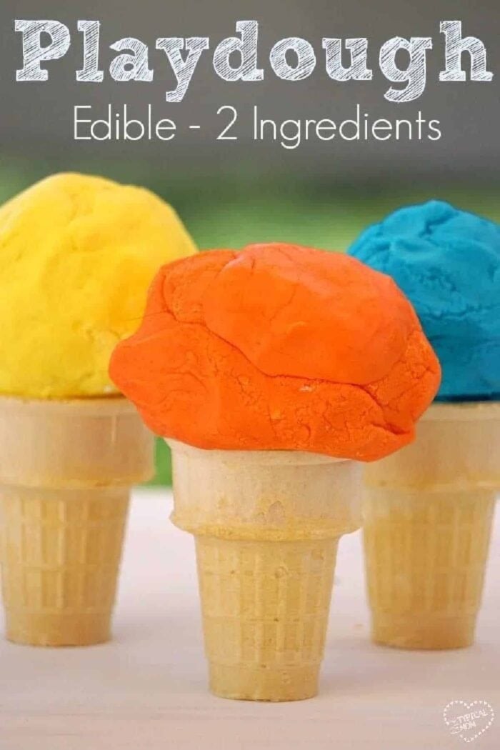Edible playdough that your kids will love! A simple playdoh recipe that is perfect for young children and fun to play with, even toddlers. #edible #playdough #playdoh #dough #craft #activity #rainyday #preschool #kindergarten #frosting Three ice cream cones topped with colorful scoops of edible playdough in yellow, orange, and blue sit on a table.