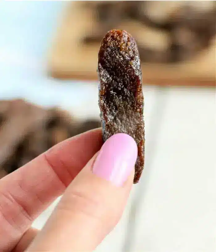 A hand holding a piece of air fryer beef jerky