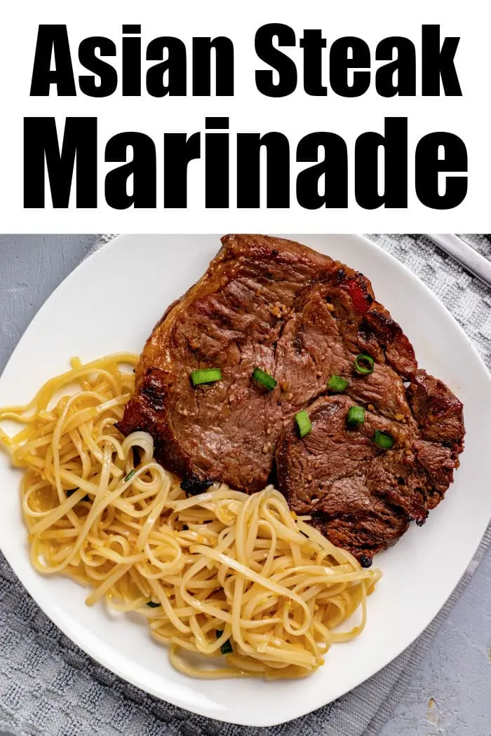 A white plate features grilled steak topped with chopped green onions, accompanied by a side of noodles. The text "Asian Steak Marinade" is displayed at the top. The plate rests on a gray surface with a light-colored napkin partially visible.