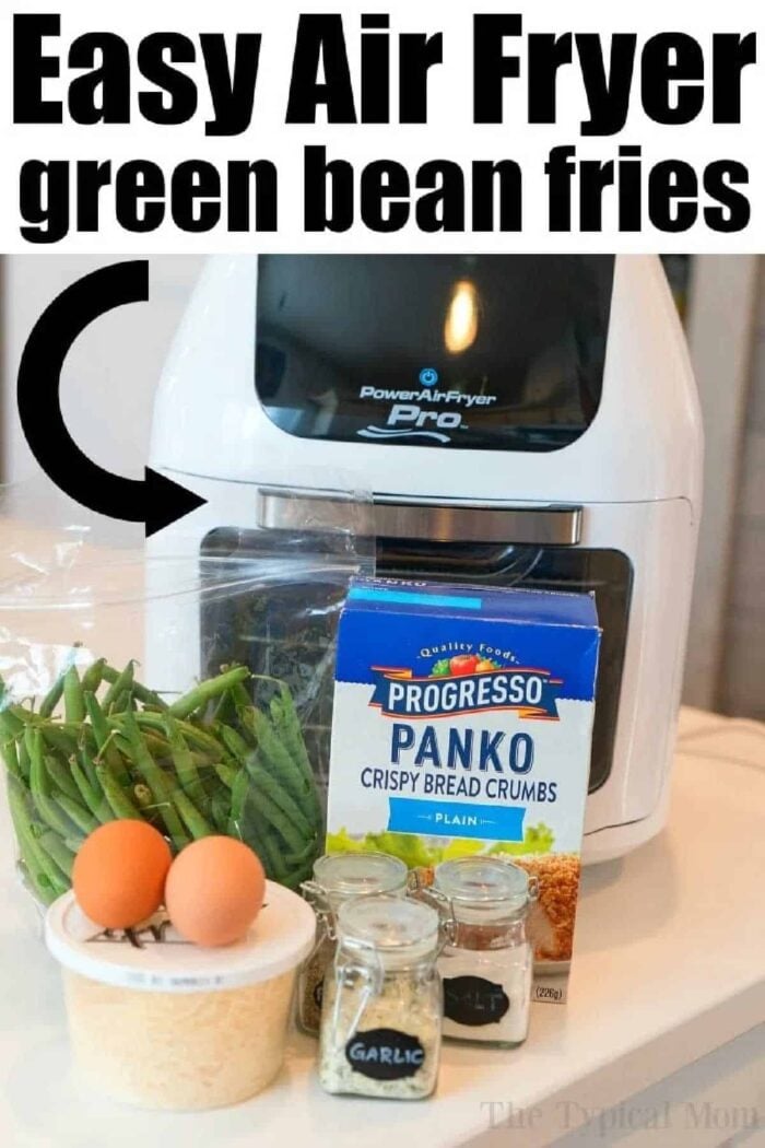 Air fryer green beans are a great snack or side dish with any meal. Crispy and crunchy vegetables covered in Panko bread crumbs and seasoning. #airfryerrecipes #airfryer #greenbeans #greenbeanfries #airfryergreenbeanfries #airfryergreenbeans #thetypicalmom Air Fryer Green Bean Fries made with crisp green beans, eggs, Panko bread crumbs, Parmesan, garlic powder, and onion powder are arranged on a counter—perfect for a healthy and delicious snack.