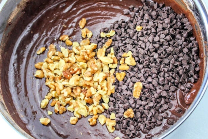 Chocolate batter for devil's food brownies with chopped walnuts and chocolate chips in a mixing bowl.