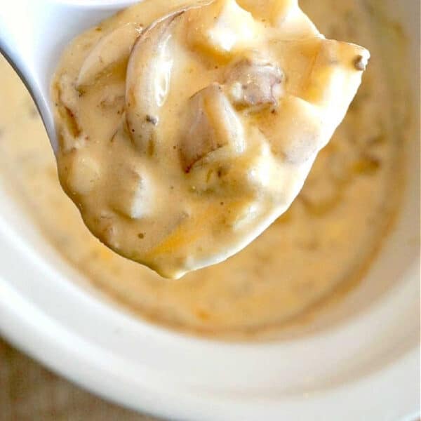 A close-up of a spoonful of creamy mushroom soup, reminiscent of the richness found in crockpot loaded baked potato soup, over a white pot.
