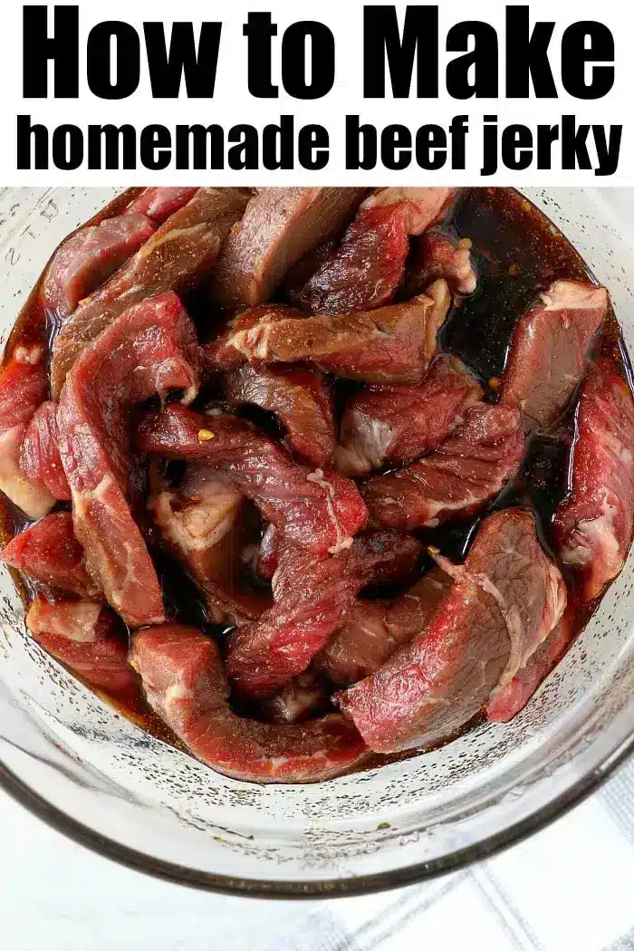 A glass bowl containing marinated strips of raw beef is shown from above. The text above the image reads, "How to Make homemade air fryer beef jerky." The beef strips are soaking in a dark sauce, appearing ready for the next step in the jerky preparation process.