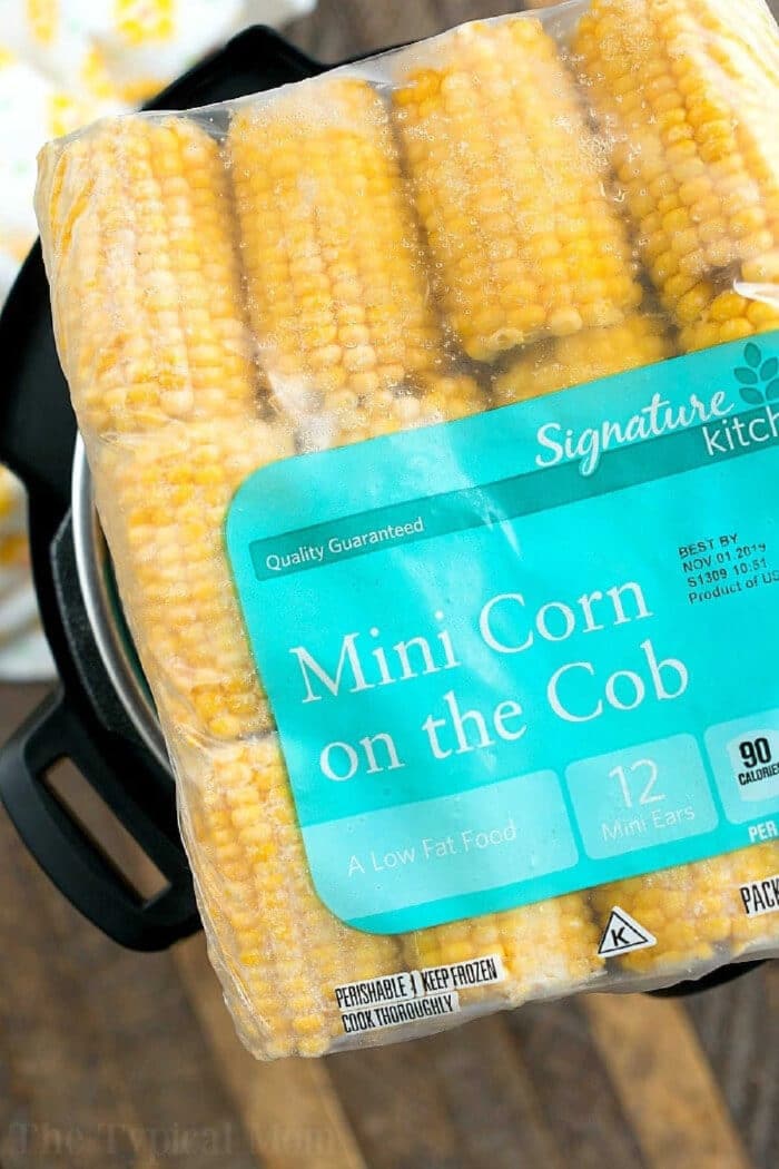 A package of Signature Kitchens Mini Corn on the Cob, containing 12 mini ears, held over a pot&mdash;perfect for making instant pot corn in no time.