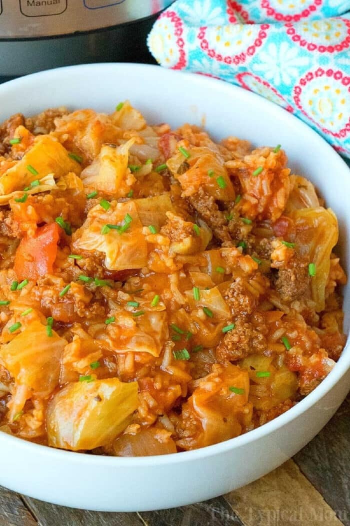 A white bowl filled with a hearty instant pot stuffed cabbage casserole, featuring ground beef in a rich tomato-based sauce.