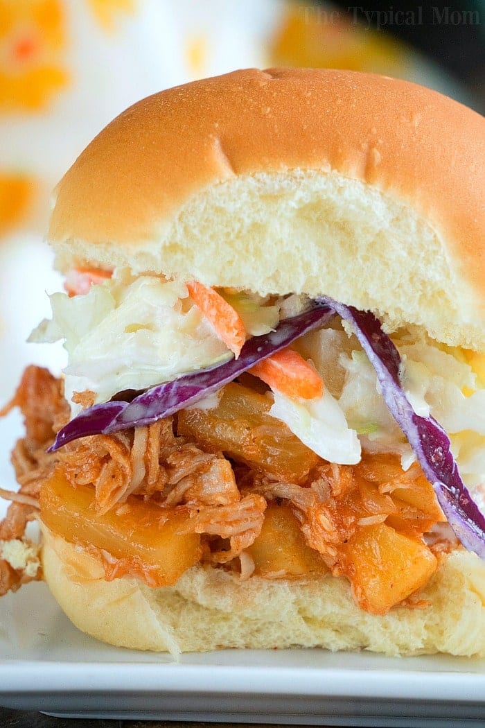 Easy Instant Pot pork shoulder recipe you will love. Amazing barbecue pulled pork sandwiches made in your pressure cooker that even my little one loves. Juicy pork usually takes all day to get this tender but in your Instant Pot it takes less than a few hours to fall apart. #pulledpork #pork #instantpot #pressurecooker #instantpotrecipes #thetypicalmom Pulled pork sandwich made from an instant pot pork shoulder recipe, topped with pineapple and coleslaw on a bun.