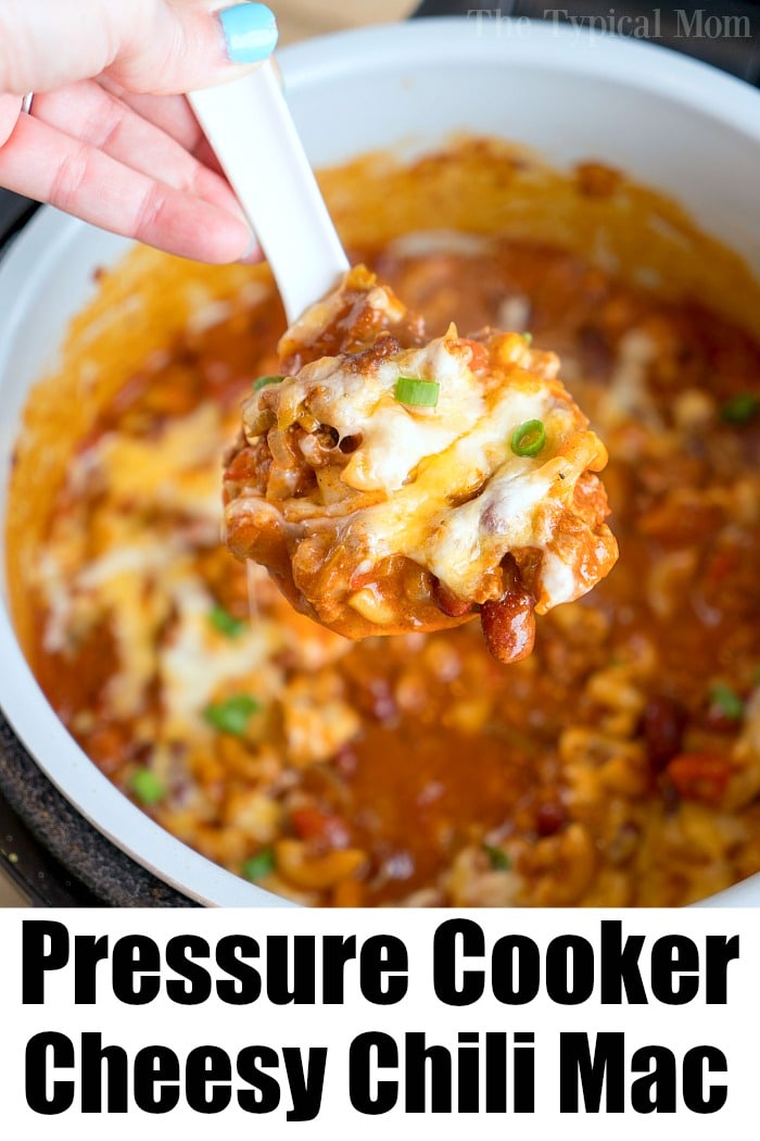 A hand holds a spoonful of hearty pressure cooker cheesy chili mac over a pot labeled Pressure Cooker Cheesy Chili Mac.