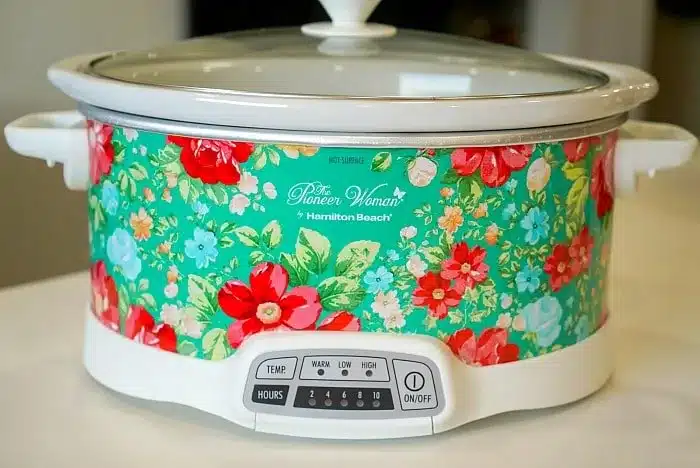 A floral design slow cooker with a white base and lid sits on a kitchen countertop, perfect for whipping up a 5 ingredient crockpot chili recipe.