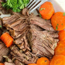 Shredded pot roast with cooked carrots and fresh parsley, prepared from a frozen roast in the Instant Pot, with a fork resting near the meat.