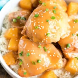 Enjoy this easy pineapple chicken: glazed chicken and pineapple chunks over rice, garnished with sesame seeds and chopped green onions.