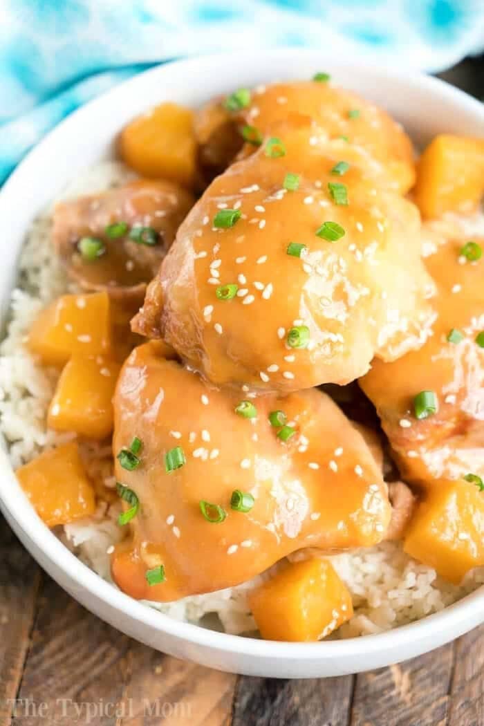 Enjoy this easy pineapple chicken: glazed chicken and pineapple chunks over rice, garnished with sesame seeds and chopped green onions.