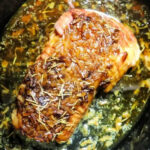 Pork roast topped with rosemary and onions, simmering in flavorful juices and Slow Cooker Pork Roast Onion Soup Mix for a savory, effortless meal.