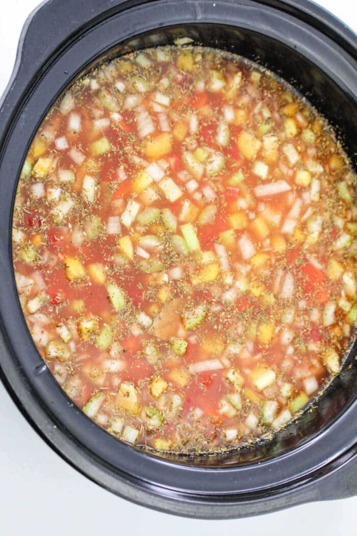 Chopped vegetables and broth in a slow cooker, perfect for making a hearty 15 Bean Soup Crock Pot recipe.