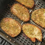 Seasoned pork chops, or pork steak in air fryer, cook to golden brown perfection, evenly spaced in the basket.