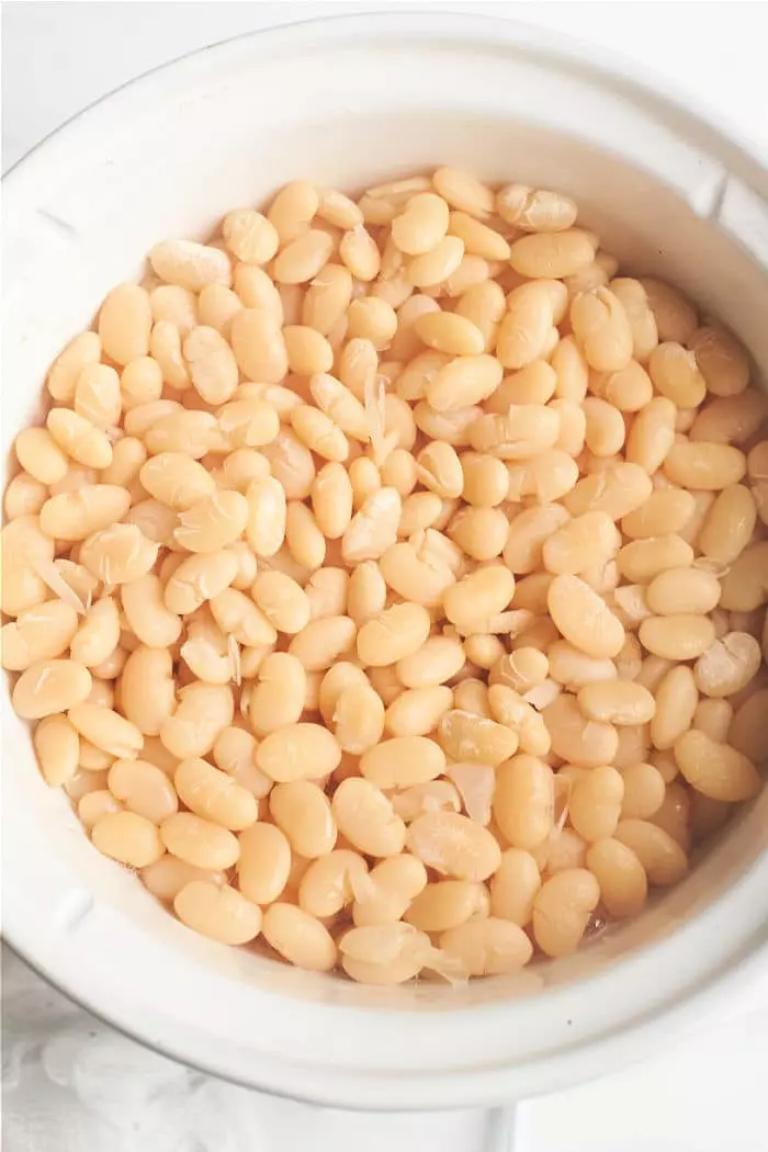 A white bowl filled with numerous Great Northern beans.