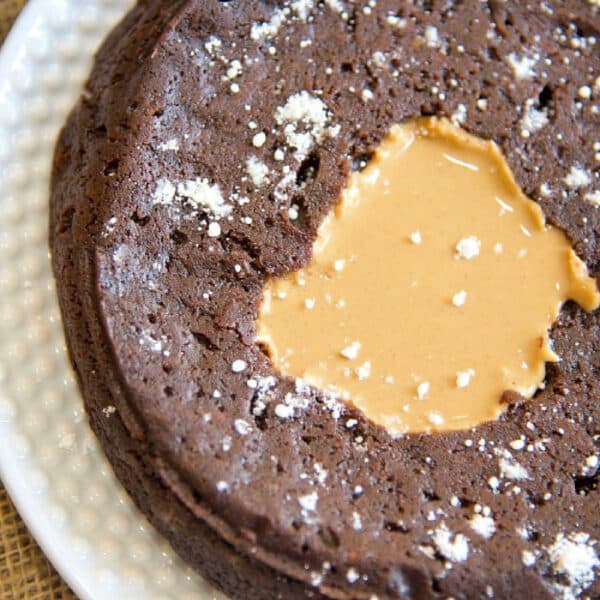 pressure cooker brownie with a melted peanut butter center, sprinkled with powdered sugar on a white plate—perfect for fans of pressure cooker brownies seeking a quick, decadent treat.