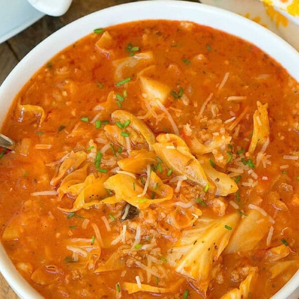 A bowl of hearty slow cooker stuffed cabbage soup with a rich tomato broth, shredded cabbage, rice, and fresh herbs on top.
