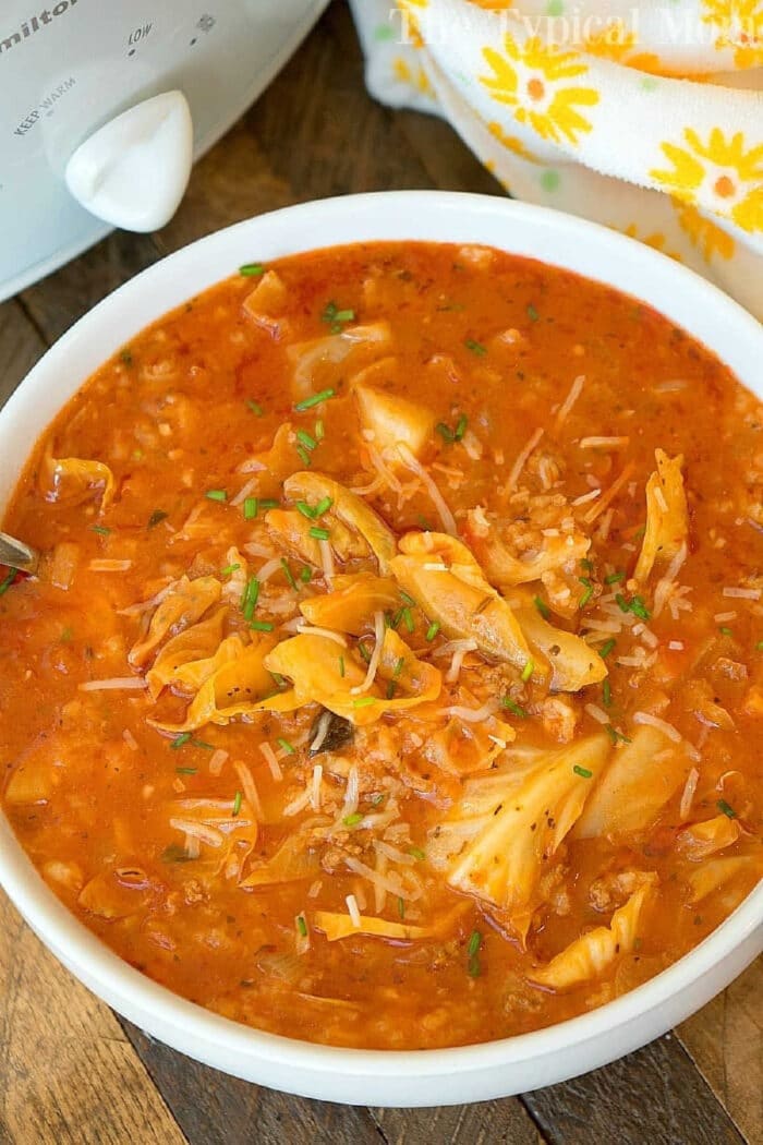 Slow cooker stuffed cabbage soup recipe your family will love! Unstuffed cabbage soup you could call it and cooks on it's own all day in your crockpot. If you love bold flavors this homemade cabbage soup will bring you back to your childhood for sure. #crockpot #slowcooker #stuffed #cabbage #unstuffed #soup #recipe #homemade #easy A bowl of hearty slow cooker stuffed cabbage soup with a rich tomato broth, shredded cabbage, rice, and fresh herbs on top.