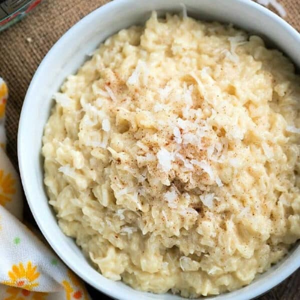 A bowl of creamy coconut rice pudding topped with shredded coconut and a sprinkle of cinnamon.