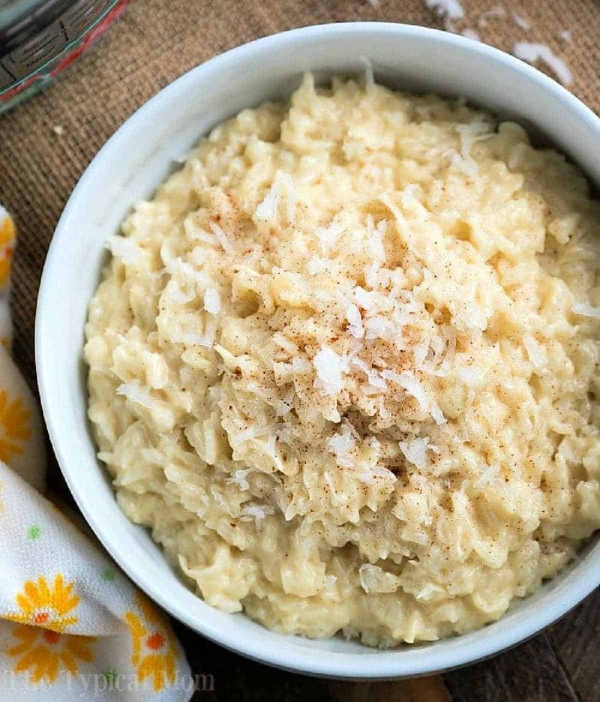 A bowl of creamy coconut rice pudding topped with shredded coconut and a sprinkle of cinnamon.