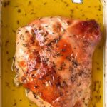 A fully cooked turkey breast confit is sitting in a rectangular yellow baking dish filled with oil. The turkey breast appears browned with some herbs sprinkled on top. The title "Turkey Confit" is written at the top of the image.