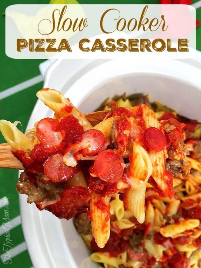 A wooden spoon lifts pasta with sauce, sausage, and pepperoni from a slow cooker pizza casserole.