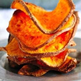 A stack of crispy, homemade sweet potato chips air fryer-style sits on a plate, perfectly golden and delicious.