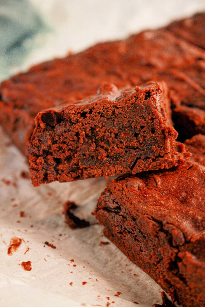 Close-up of a rich black bean brownie with mix, showcasing its soft and dense texture, placed on parchment paper.