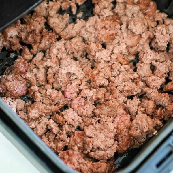 Air fryer ground beef cooked in the basket, with some pink areas still visible.