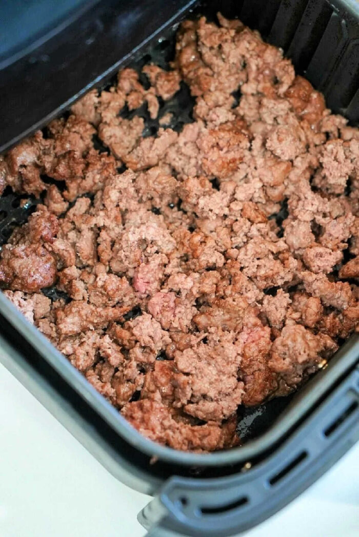 Air fryer ground beef cooked in the basket, with some pink areas still visible.