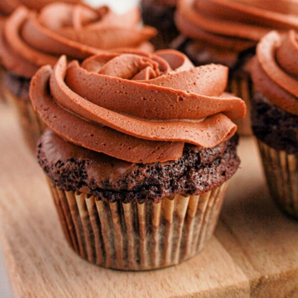 Brownie cupcakes with swirled frosting are artfully arranged on a wooden board, creating an irresistible treat.