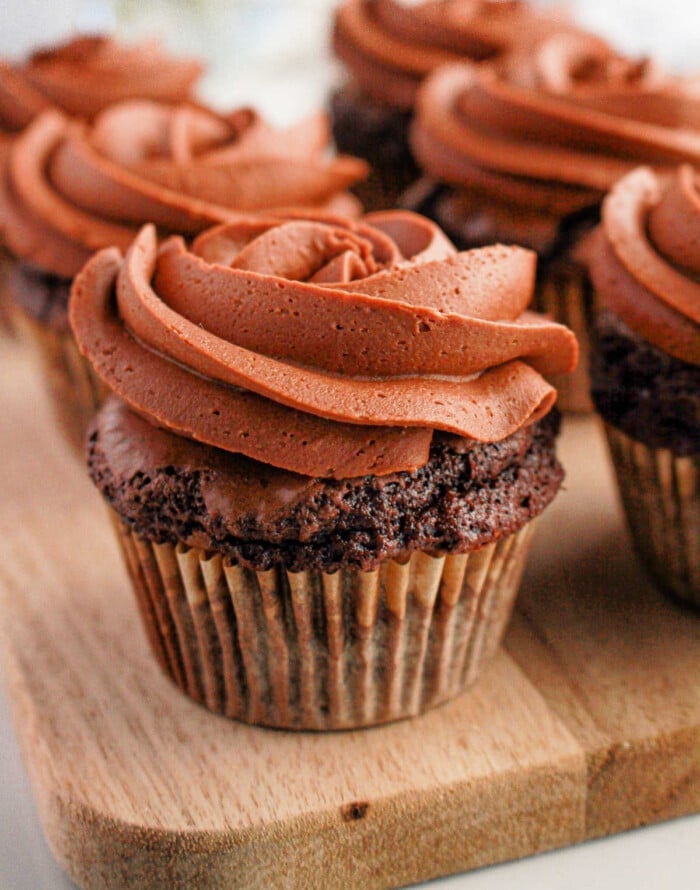 Brownie cupcakes with swirled frosting are artfully arranged on a wooden board, creating an irresistible treat.