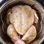 Whole uncooked chicken seasoned with spices in a metal pot, perfect for meal prep during busy weeks, rests on a gray surface.