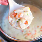 A spoonful of creamy chicken pot pie soup with vegetables held over an Instant Pot.