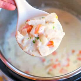 A spoonful of creamy chicken pot pie soup with vegetables held over an Instant Pot.