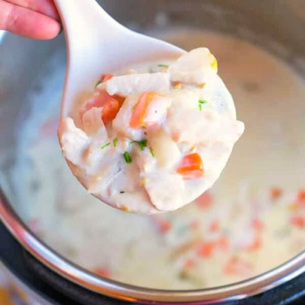 A spoonful of creamy chicken pot pie soup with vegetables held over an Instant Pot.