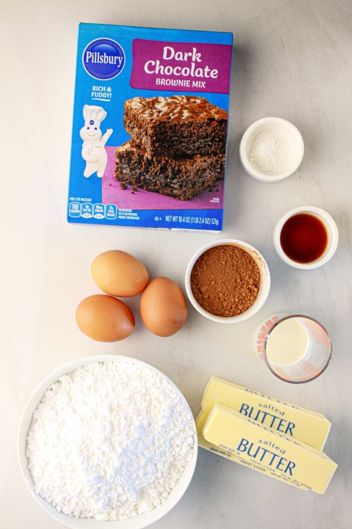 For delicious brownie cupcakes, gather baking essentials: brownie mix, eggs, butter, cocoa, flour, vanilla extract, and milk.