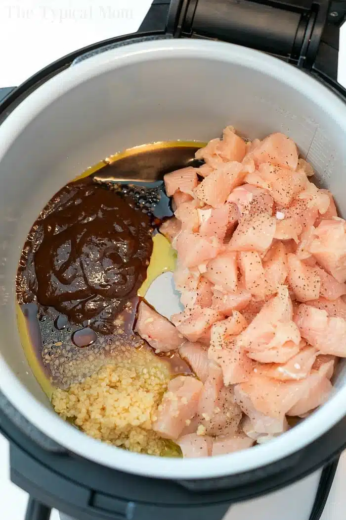 Diced raw chicken, sauce, oil, and minced garlic in an Instant Pot before cooking make the perfect base for pressure cooker cashew chicken.