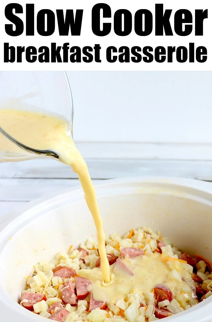Egg mixture is poured into a slow cooker over chopped sausage, slow cooker cheesy potatoes, and cheese to make a hearty breakfast casserole.