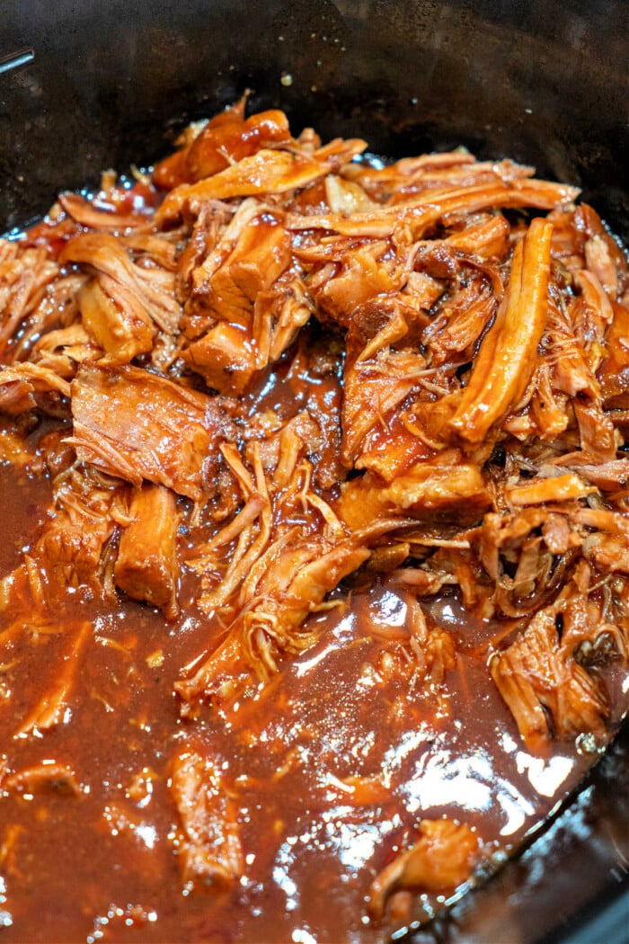 Savor the taste of pulled pork simmering in a rich barbecue sauce, effortlessly crafted with just 2 ingredients in a slow cooker.