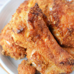 A plate of golden-brown Bisquick oven-fried chicken drumsticks and thighs.